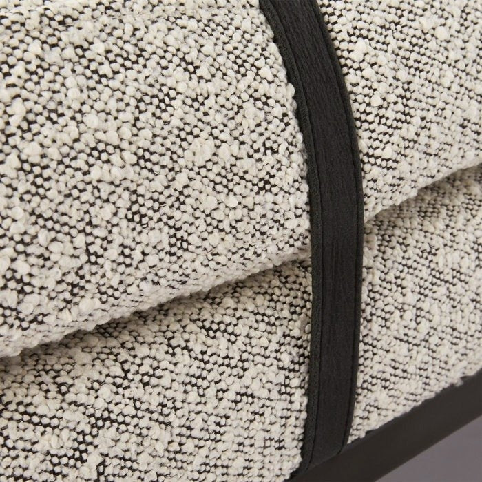 Close-up of natural cream boucle upholstery on an end-of-bed bench, showing textured looped fabric with contrasting black trim strap and a dark wood base.