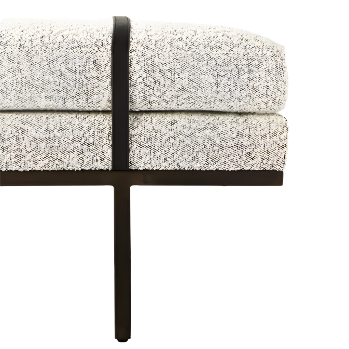 Close-up of the bench end showing natural boucle upholstery with a textured cream-and-gray weave, stacked seat cushions and a dark metal leg with a vertical strap accent.
