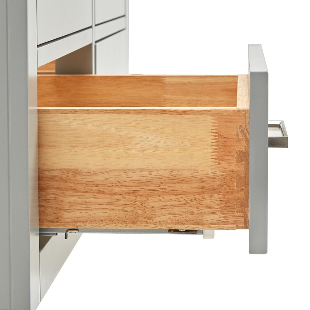 Open solid wood drawer showing dovetail joints and natural wood grain, paired with a stone-colored vanity front and rectangular brushed-nickel handle.