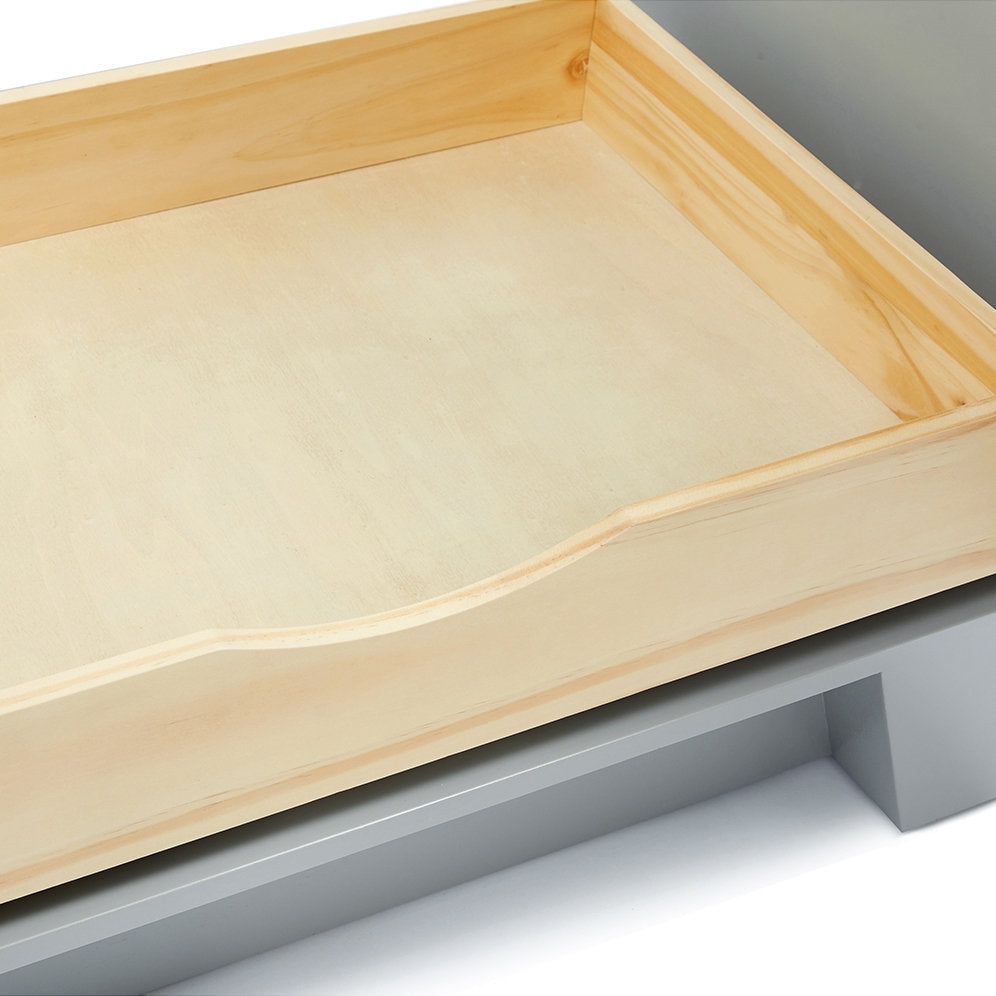 Close-up of a light solid-wood vanity drawer interior with a shallow scalloped front cutout and natural finish, shown above a gray painted vanity base.