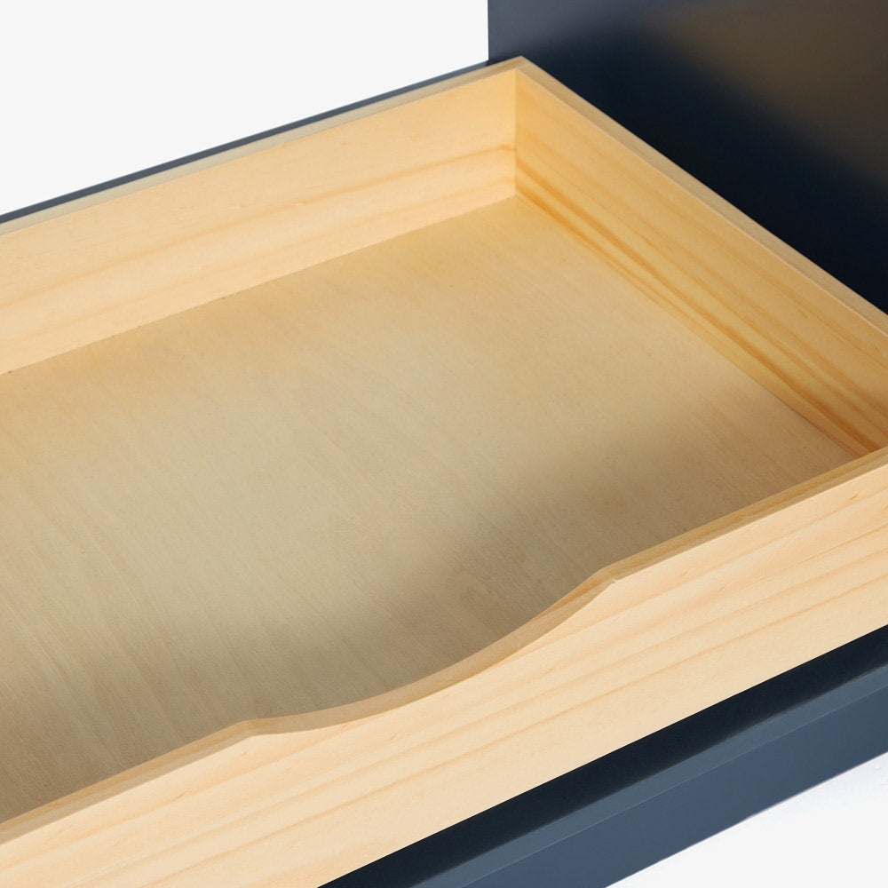 Close-up of a light solid wood drawer interior with a curved integrated finger pull and smooth plywood bottom, framed by the dark bronze exterior of a modern bathroom vanity.