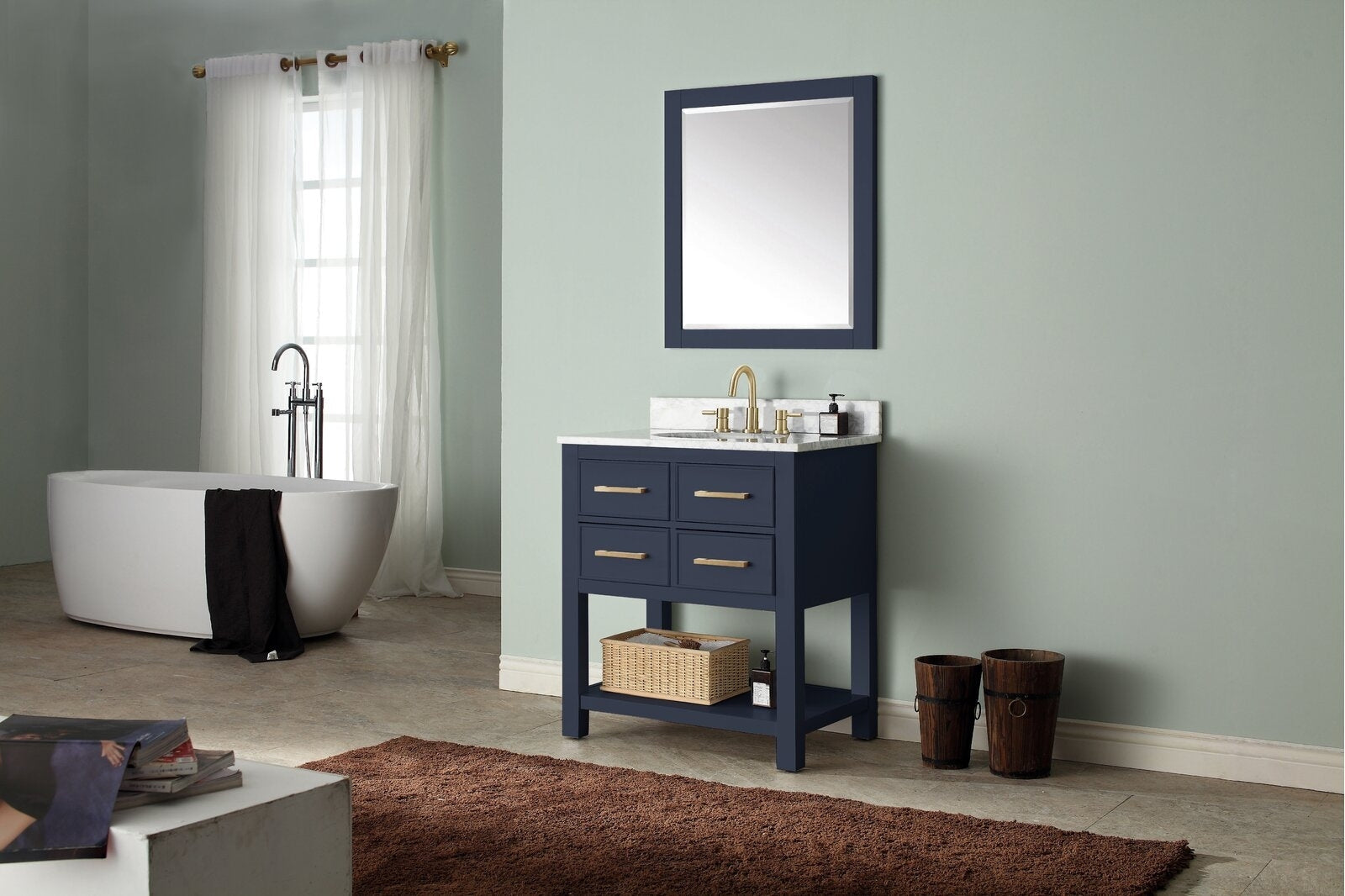 Contemporary solid wood freestanding 31-inch single-sink bathroom vanity in stone finish with stone countertop and ceramic basin, brass faucet and hardware, four drawers above an open shelf with wicker basket, shown with framed mirror.