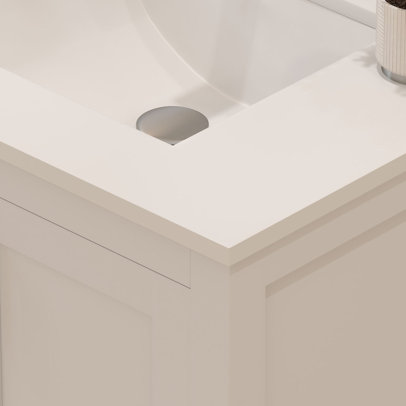 Close-up of a stone-colored vanity top with an integrated white sink and round chrome drain set on a modern solid-wood cabinet featuring recessed panel detailing.