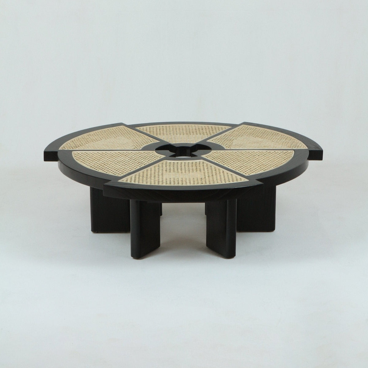 Low round coffee table in natural oak with woven cane inset divided into six radial panels, thick circular frame and short chunky pedestal legs, shown on a plain white background.