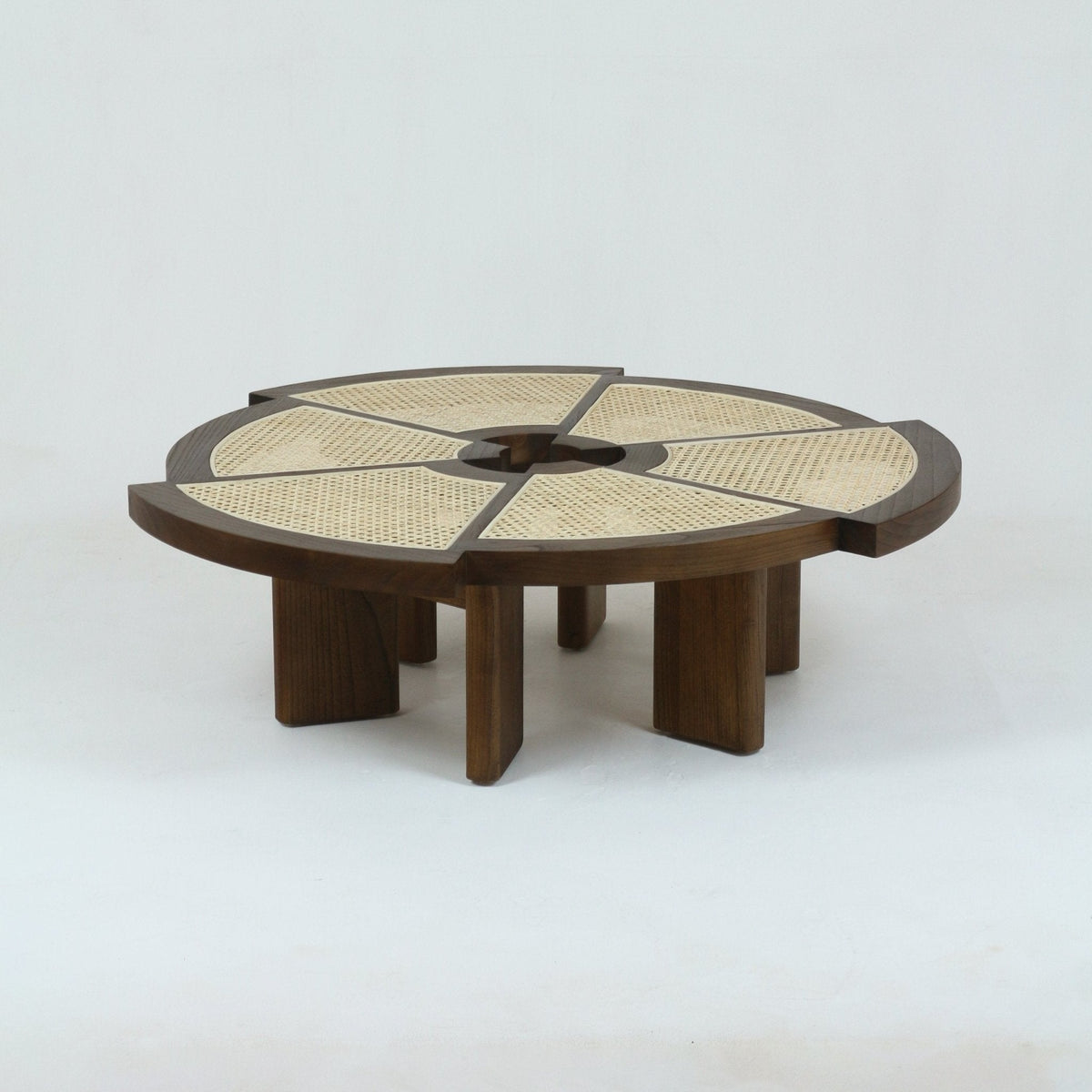 Low round mid-century modern coffee table in natural oak with six cane-inset wedge panels radiating from a central opening and thick sculpted solid-wood legs.