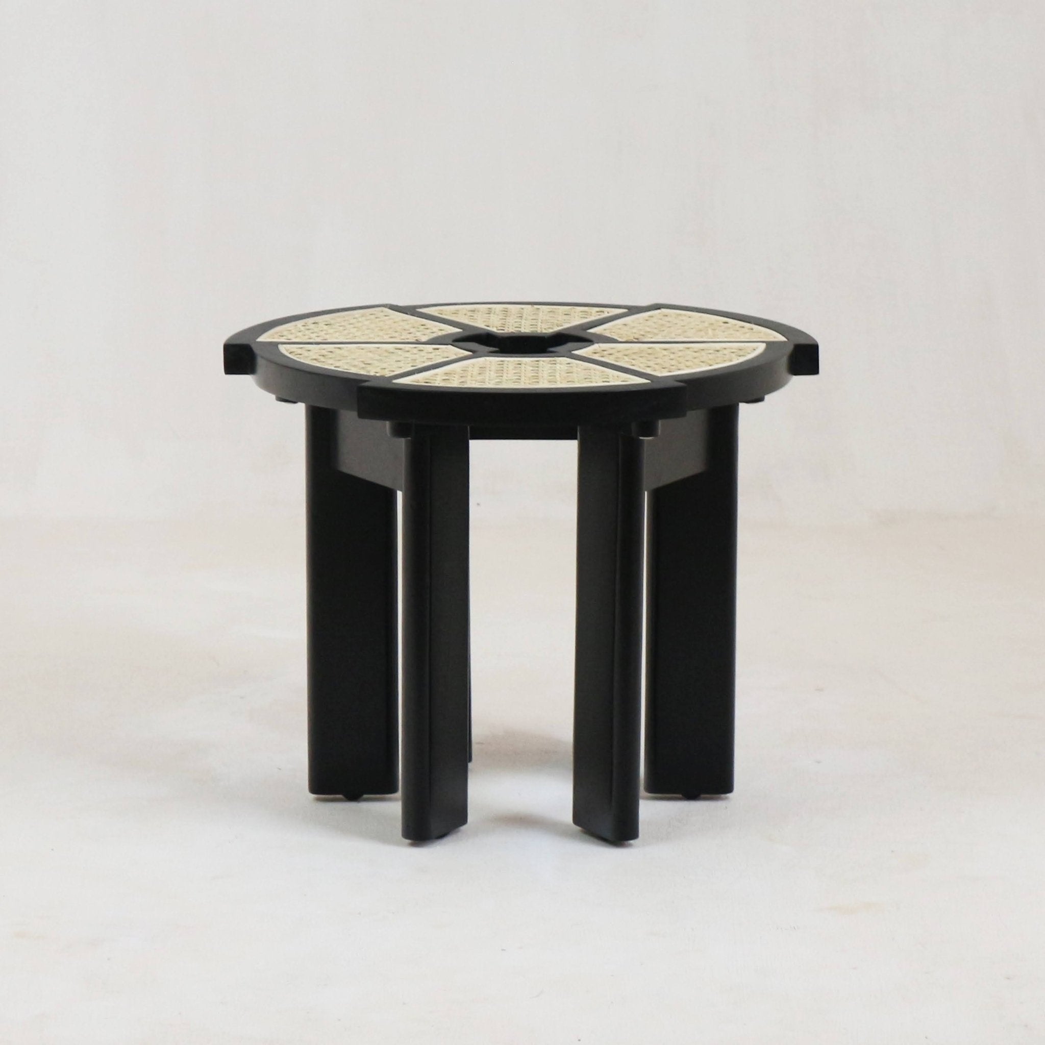 Round modern side table with glossy black solid-wood frame and natural cane-woven segmented top, supported by clustered vertical black wood legs.