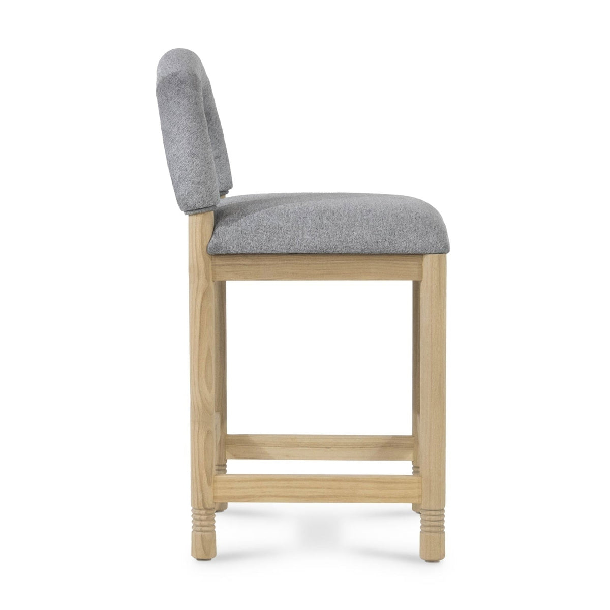 Side profile of a counter-height stool with a natural oak frame and light gray bouclé fabric seat and low back, showing square legs, dual front foot rails and subtle turned detailing on the leg ends.