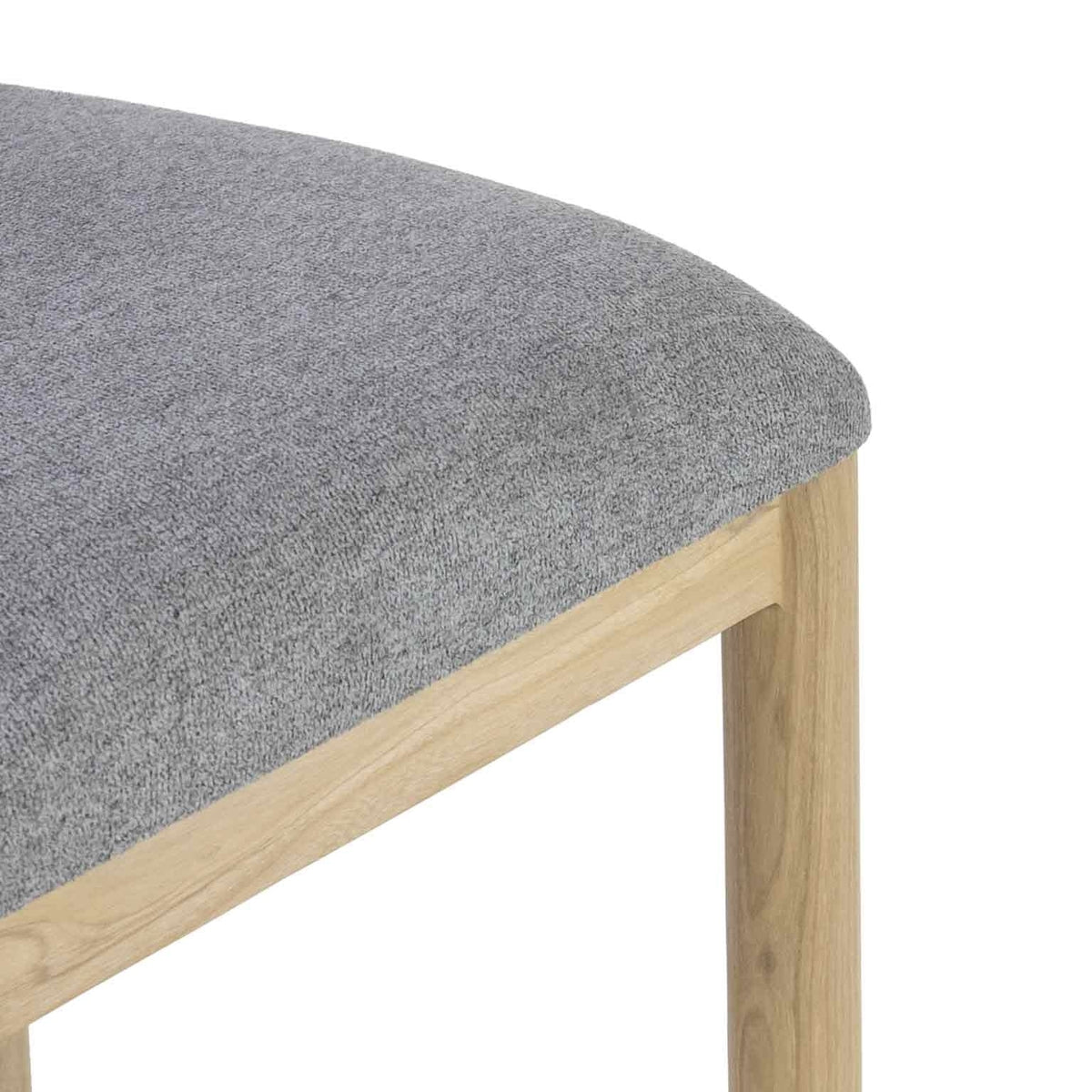 Close-up of a gray boucle upholstered seat showing textured fabric on the cushion and the natural oak apron and leg of a coastal-contemporary bar/counter stool.
