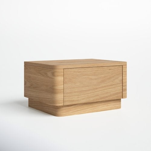 Contemporary low nightstand in natural oak solid wood with a single flush drawer, rounded corners and recessed plinth base, shown on a white background.