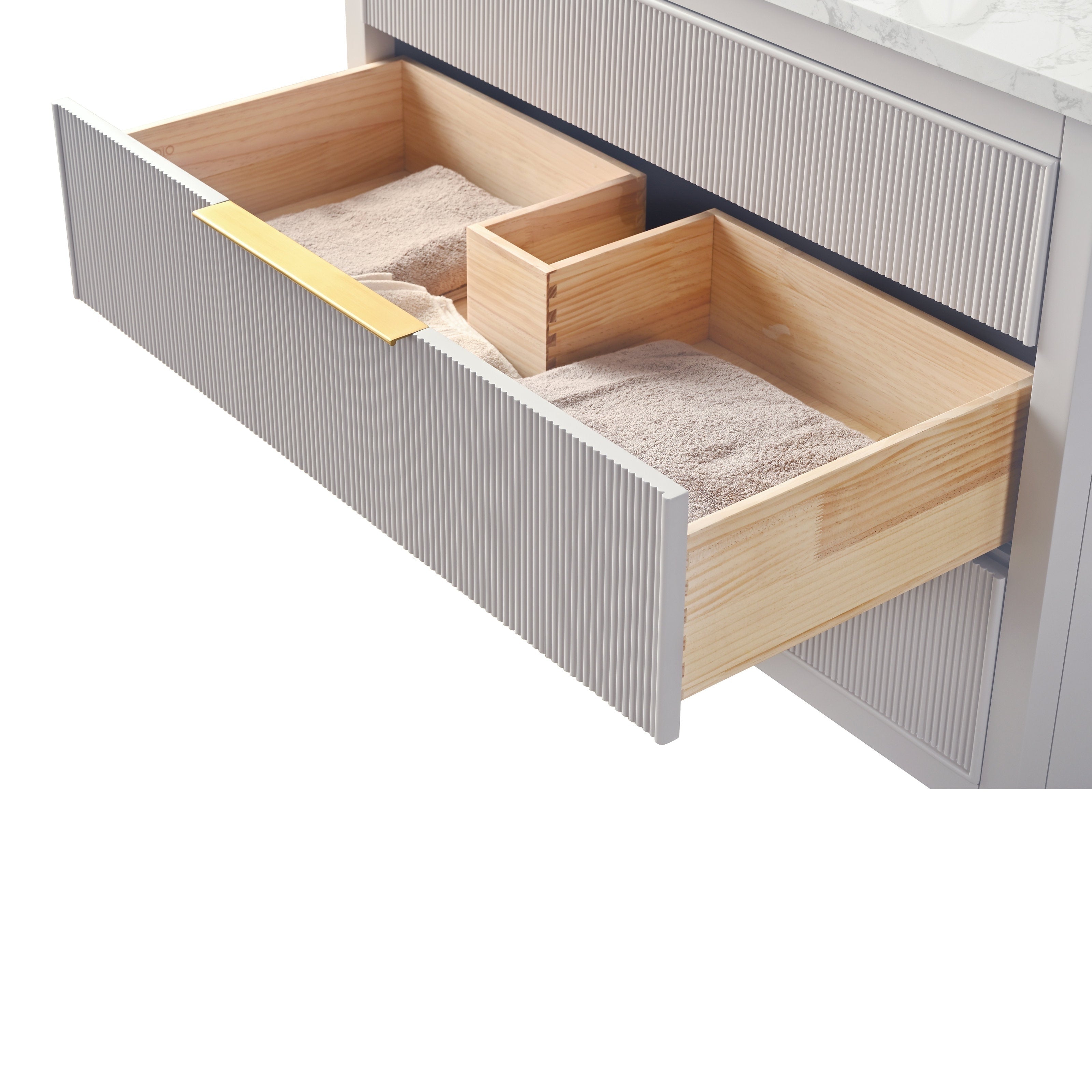 Open vanity drawer showing light solid-wood interior, ribbed stone-colored front panel, slim gold handle and folded beige towels beneath a white stone countertop.