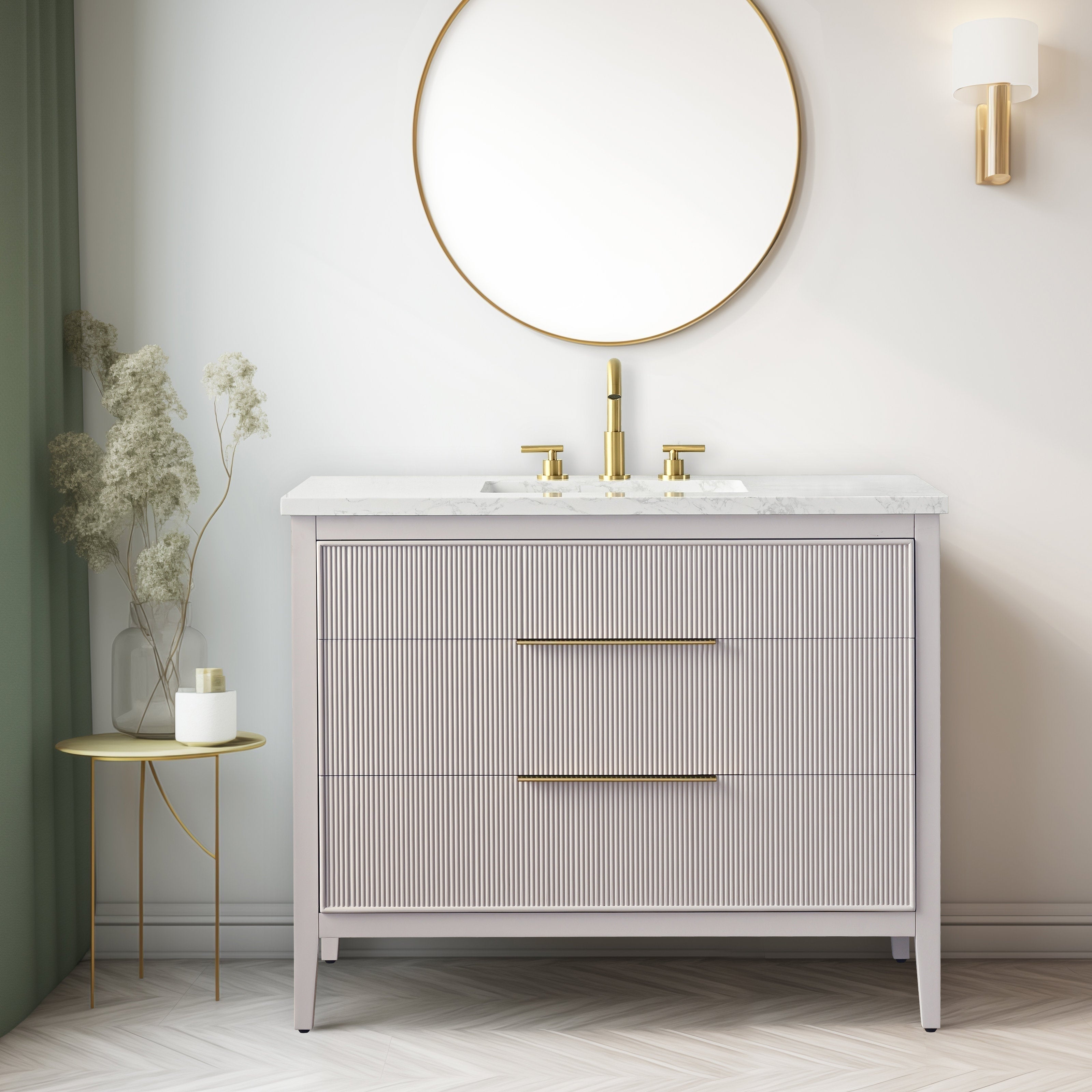 Modern solid wood 42-inch single-sink bathroom vanity in stone finish with a marble-look stone top, fluted drawer fronts and gold faucet and pulls, styled with a round mirror, wall sconce and side table with vase.