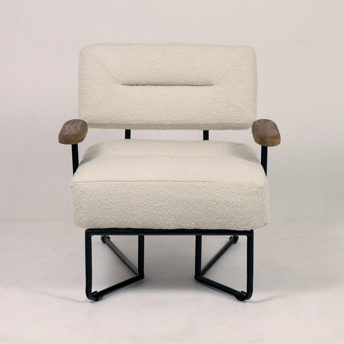 Front-facing modern lounge chair upholstered in cream boucle fabric with rounded walnut-toned wooden arm pads and a black metal sled-style base, mid-century modern inspired silhouette.