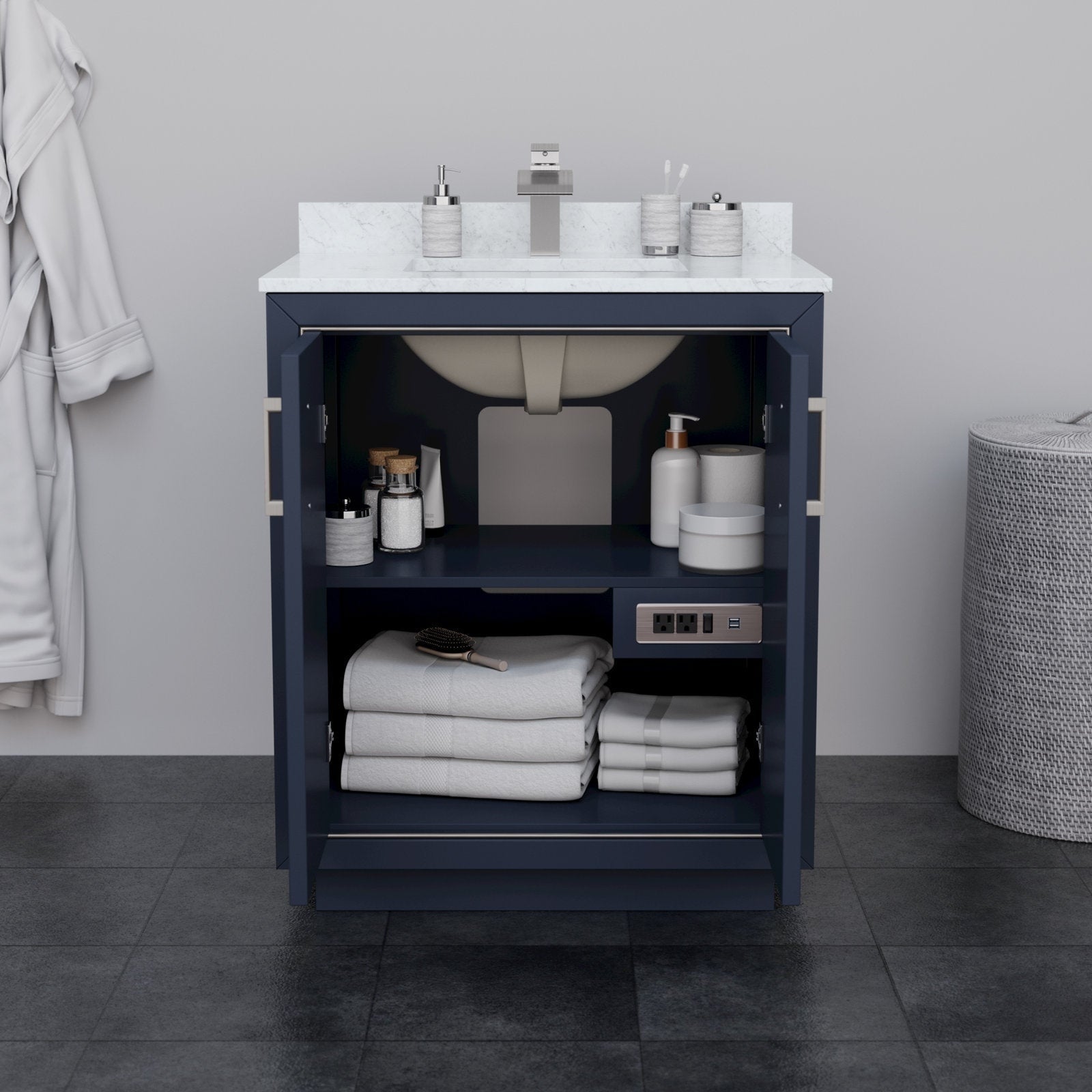Open 30-inch modern solid wood bathroom vanity with stone countertop and integrated ceramic sink, navy base with open doors showing shelf storage of folded towels, toiletries and built-in power outlets.