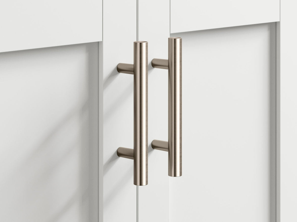 Close-up of two brushed brass-tone cylindrical bar pulls installed on stone-colored solid wood modern bathroom vanity doors, highlighting the metal finish and mounting posts.