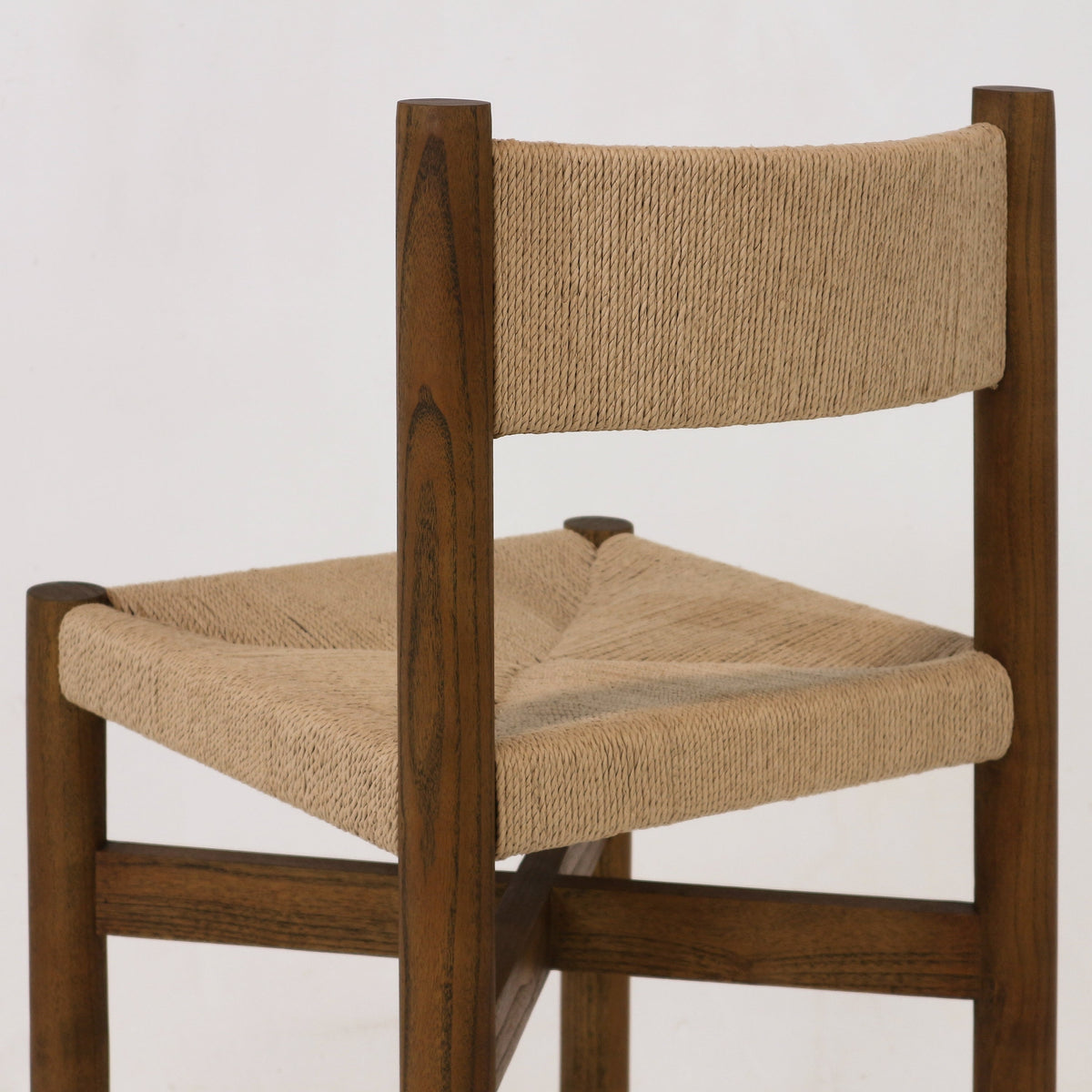 Close-up of a walnut-stained solid wood stool showing a natural papercord woven seat and matching woven backrest, highlighting the textured rope weave and warm wood grain.