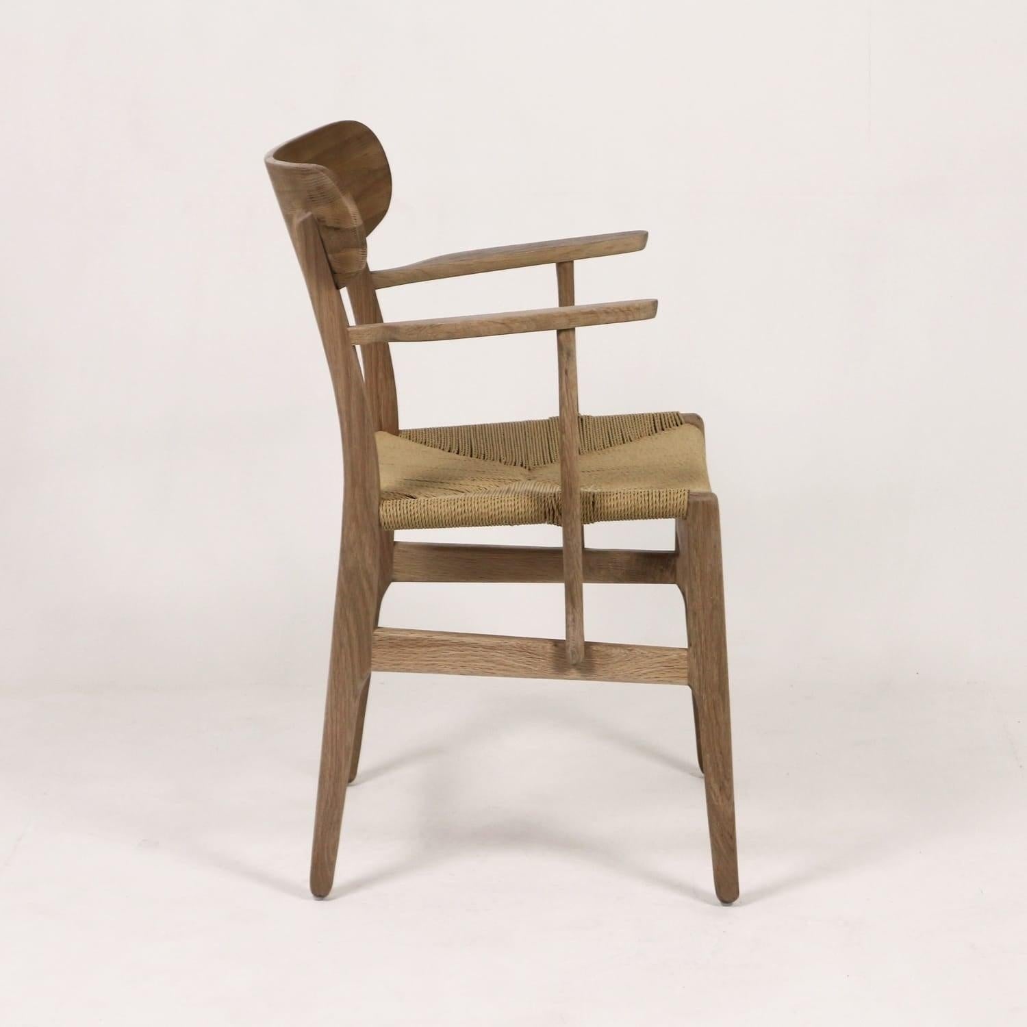 Side view of a Scandinavian-style dining chair with a light brown solid wood frame, curved slim arms and a natural woven rope seat, shown against a white studio background.