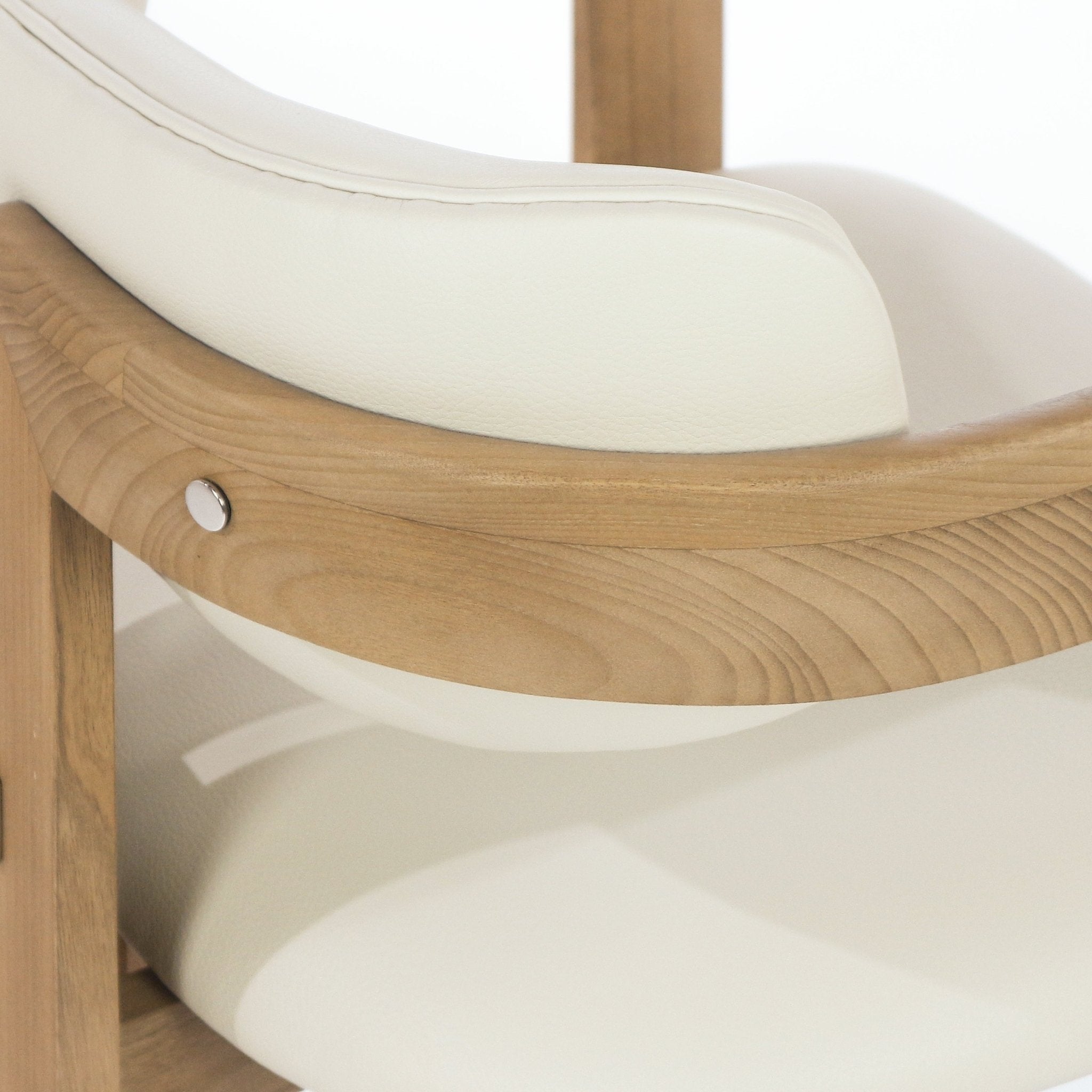 Close-up of a mid-century style dining chair armrest showing curved teak wood grain, beige leather upholstery on the seat and back cushion, and a small round metal fastener securing the frame.
