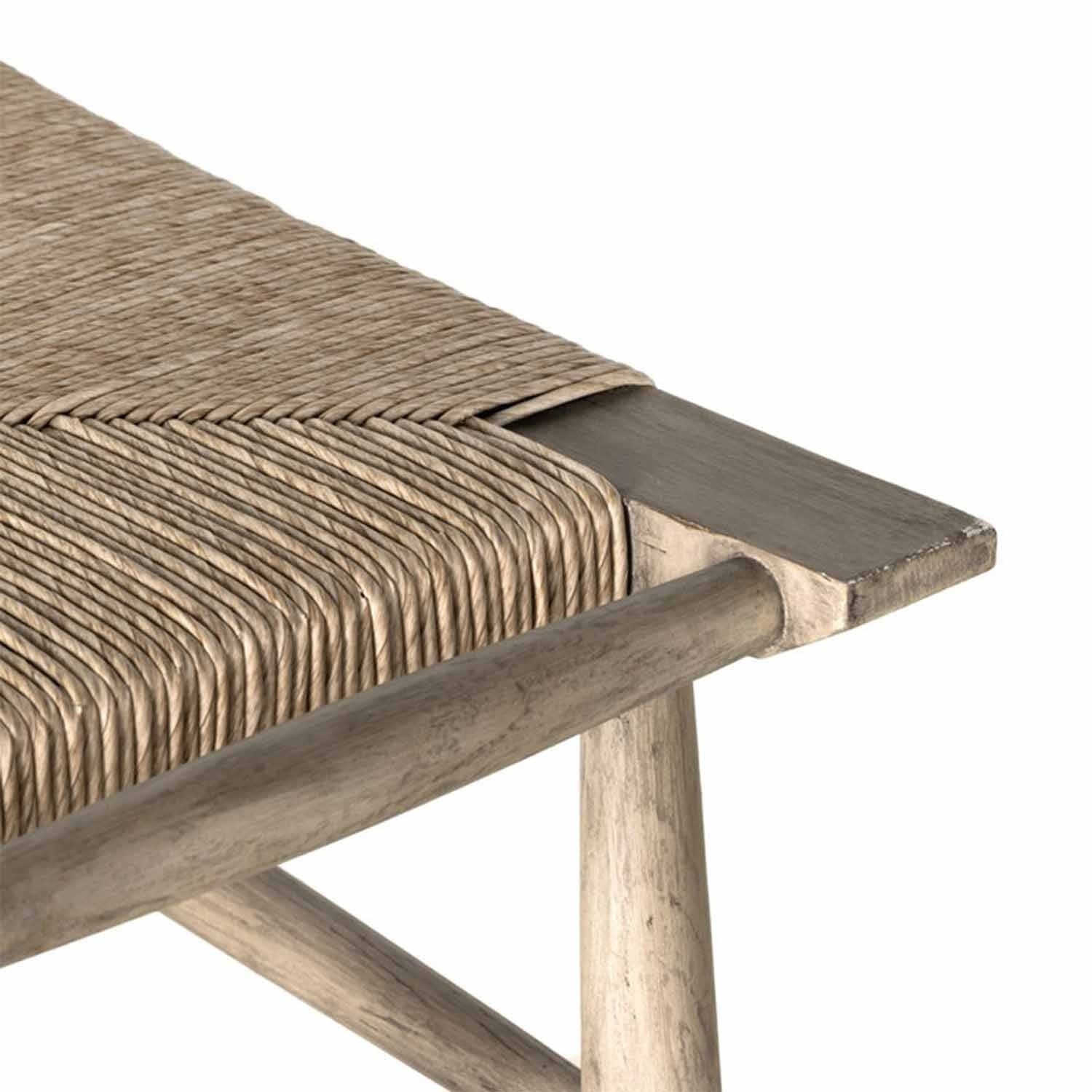 Close-up of a natural teak backless bar stool highlighting the tightly woven seat, beveled teak seat edge and rounded teak leg and stretcher with a weathered coastal finish.