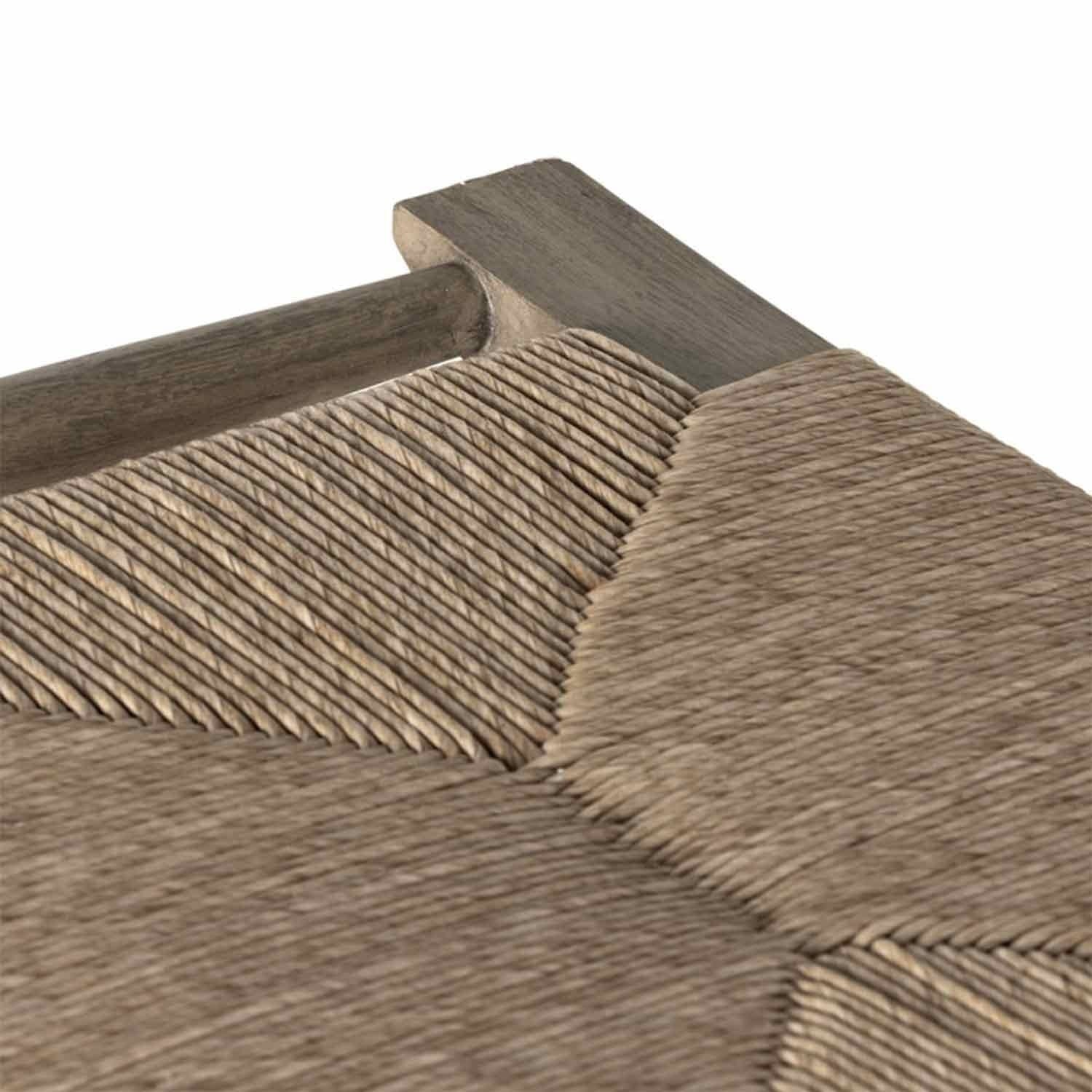 Close-up of a natural teak backless outdoor bar stool seat showing the detailed woven natural-fiber cord pattern and the teak wood frame in a coastal Scandinavian style.