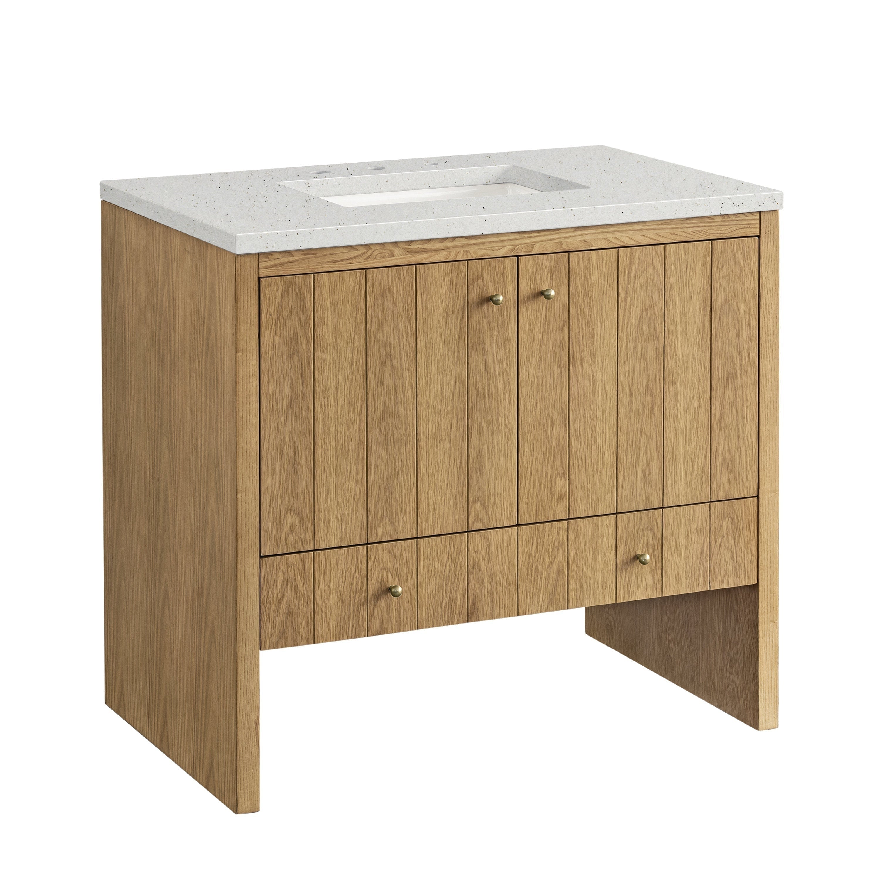 The Sala 36 Single Bathroom Vanity by NUEMA features solid oak with a light finish, vertical paneling, two central cabinet doors with brass knobs, two lower drawers, and a white speckled stone countertop with a rectangular sink cutout.