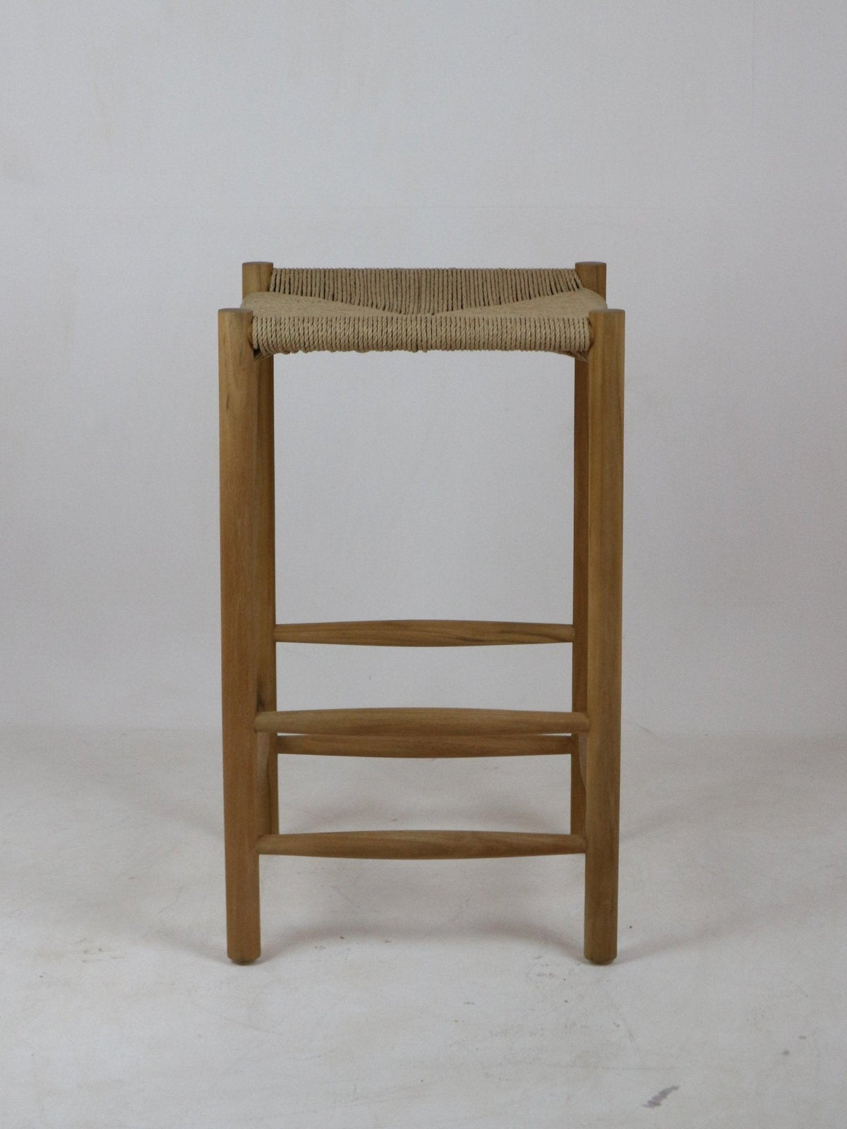 Front view of a natural solid wood bar stool with a woven beige rope seat, straight legs and horizontal wooden foot rails in a minimalist modern backless design.