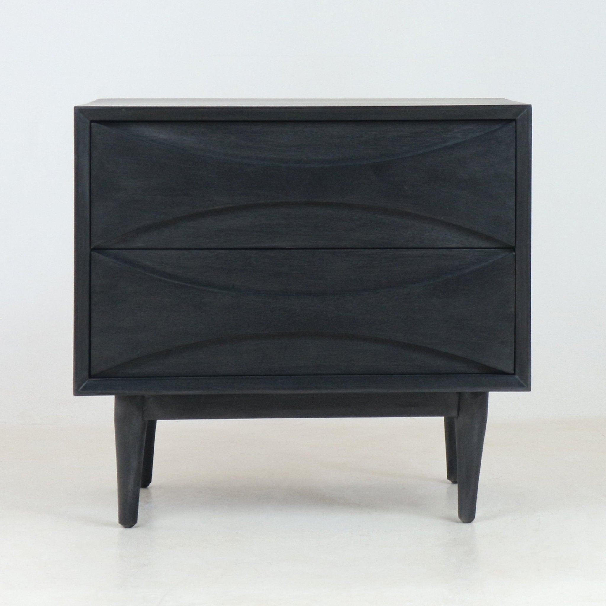 Front view of a mid-century modern solid wood nightstand in smoked black finish, with two sculpted drawers featuring curved recessed fronts and tapered legs on a plain white studio background.