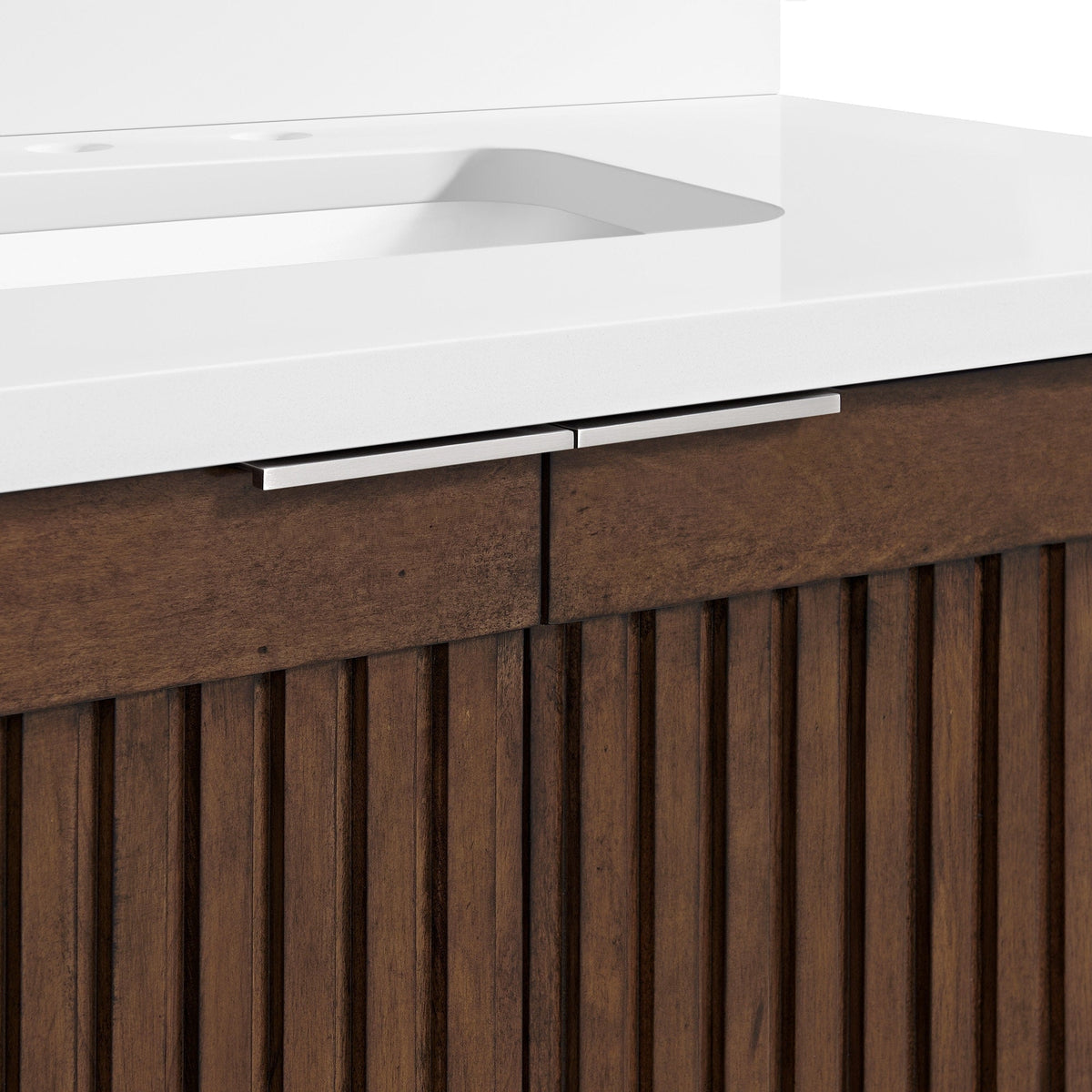 Close-up of a modern single-sink bathroom vanity showing a stone top with integrated white basin and slim brushed-metal handles above a brown solid-wood cabinet with vertical fluted panels.