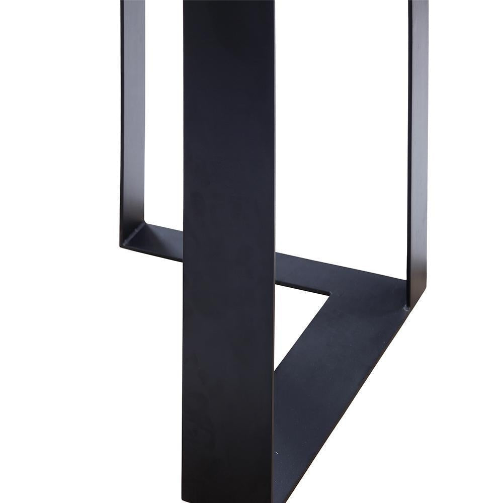 Close-up of a black steel console table leg and triangular base with a matte finish, showing welded seam and minimalist modern-industrial design.