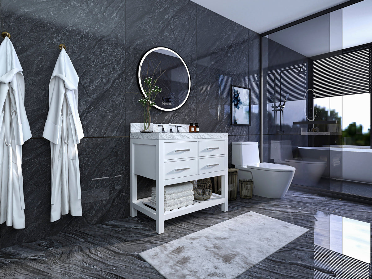 Modern solid wood freestanding 36-inch bathroom vanity in stone finish with marble top, single white ceramic sink, four drawers and open lower shelf with folded towels beneath a round mirror on dark stone walls.