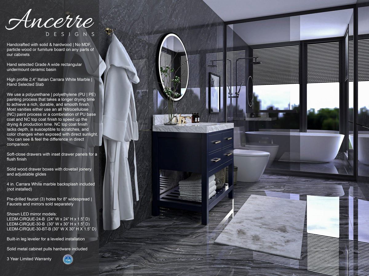 Modern solid-wood single-sink vanity in dark navy with a white Carrara-style stone countertop, round LED mirror and brushed-gold pulls, set against gray marble walls and floor beside a glass shower and freestanding tub.