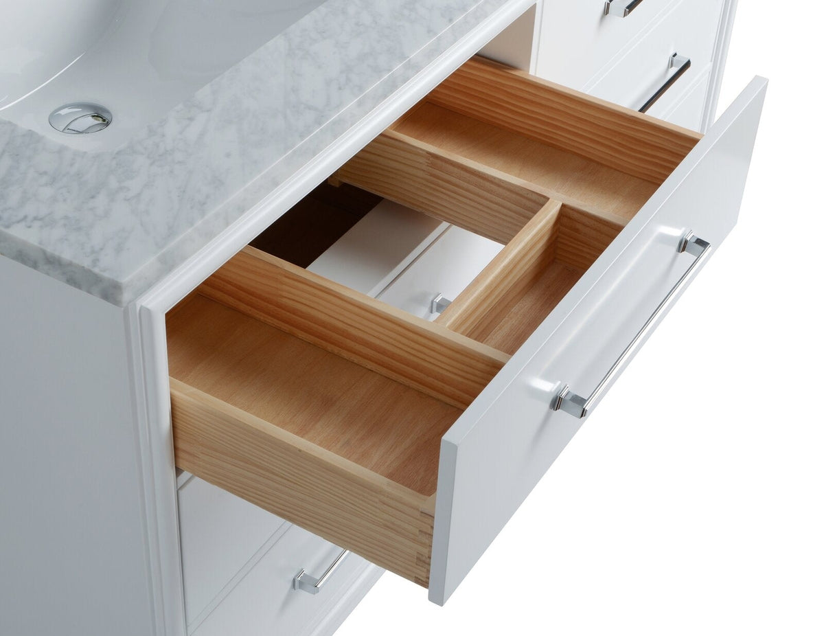 Close-up of a modern white bathroom vanity with a stone marble-look countertop and undermount ceramic sink, showing an open solid wood drawer with built-in dividers and chrome bar handle.