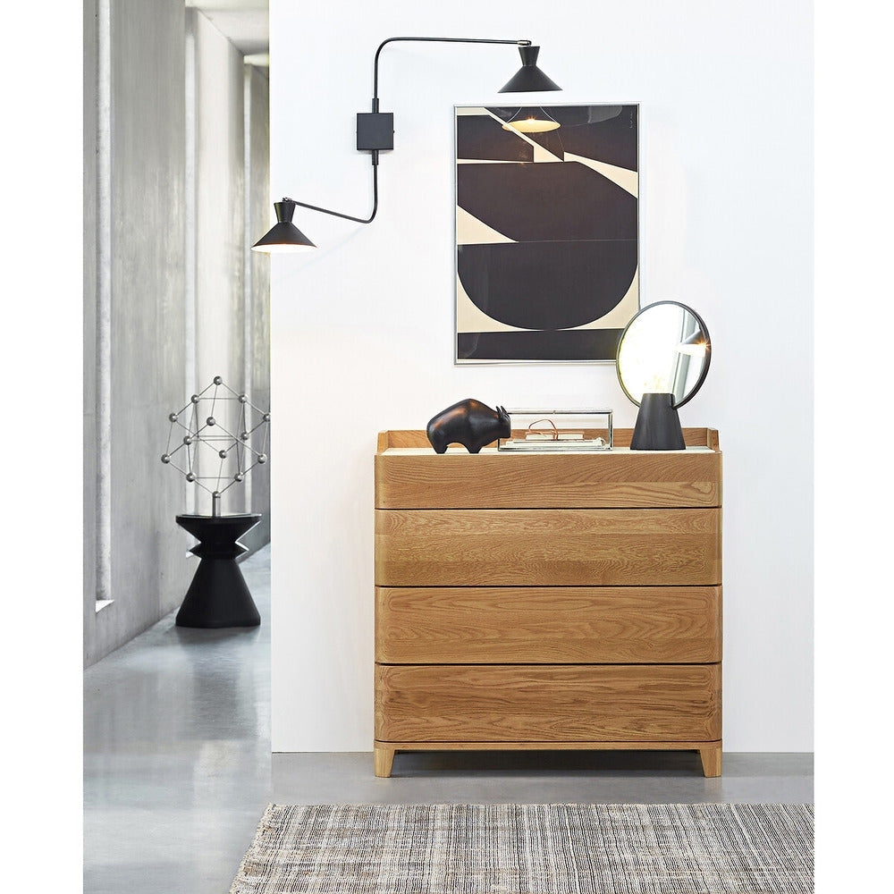 Four-drawer solid walnut armoire dresser with a linoleum top shown in a modern living vignette, styled with a round tabletop mirror, black decorative rhino, framed abstract art and a black dual-arm wall sconce.