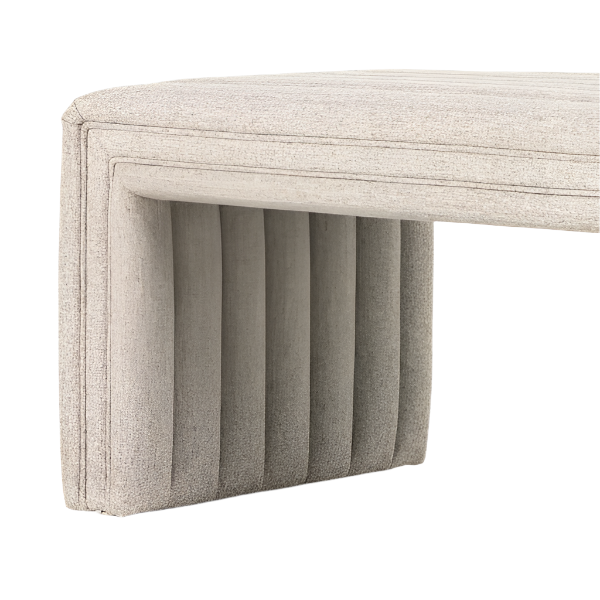 Close-up of a natural beige boucle upholstered bench end showing a cushioned top and vertical channel-tufted fabric leg in a coastal-contemporary style.