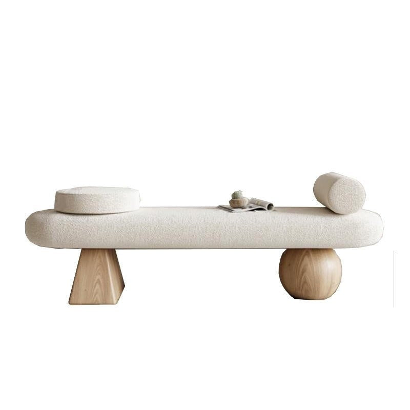 75-inch off-white boucle-upholstered end-of-bed bench with natural wood legs — one tapered geometric leg and one spherical leg — styled with a round bolster, a circular cushion and a small magazine on top.