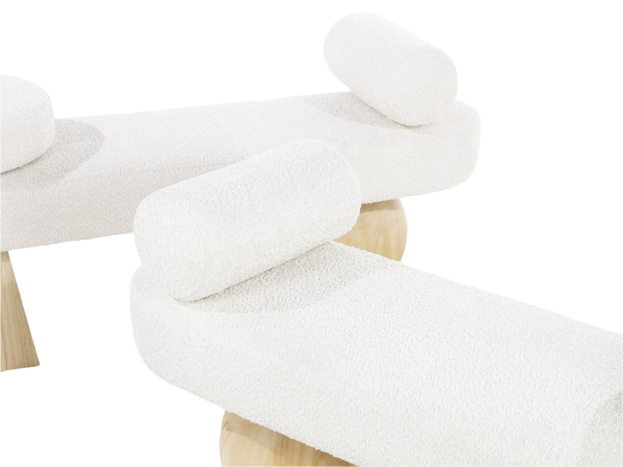 Close-up of a white boucle upholstered bench showing textured boucle fabric, cylindrical bolster pillows and rounded natural wood legs in a coastal-contemporary style.