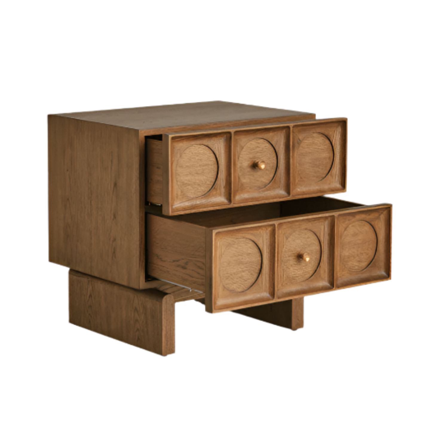Solid wood nightstand in warm brown natural finish with two stacked drawers featuring carved circular recessed panels and small brass knobs, lower drawer pulled open to show interior, contemporary glam bedside table.