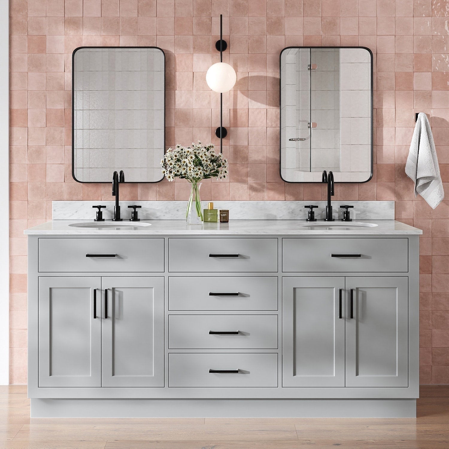 73-inch gray solid wood double-sink bathroom vanity with Giotto quartz countertop, two undermount white ceramic sinks, matte black faucets and hardware, black-framed mirrors, central globe wall sconce, vase of daisies and pink tile backsplash.