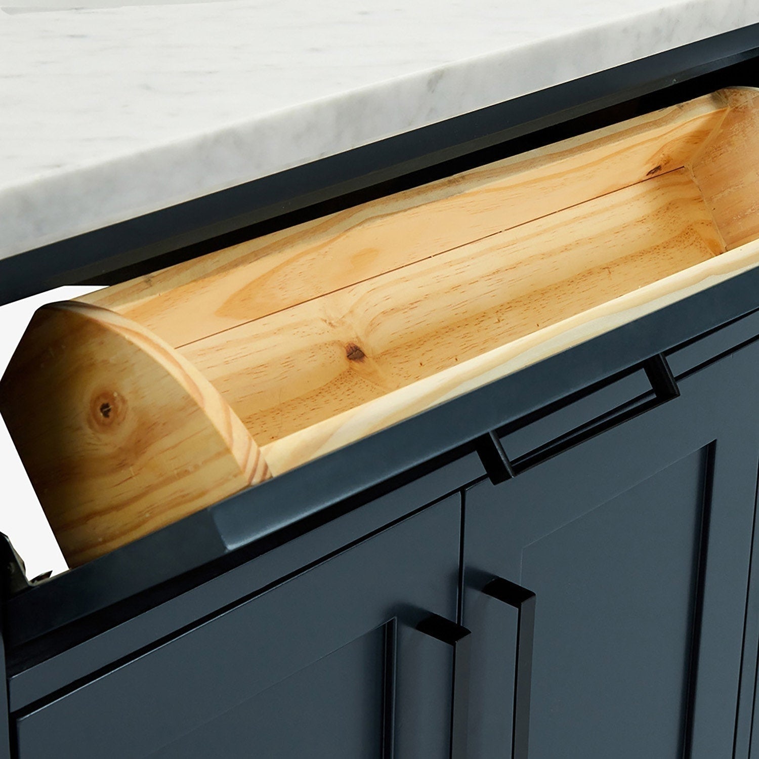 Close-up of a matte-black modern bathroom vanity with a white quartz countertop and an open top drawer revealing a natural solid wood interior and a slim rectangular black drawer handle.