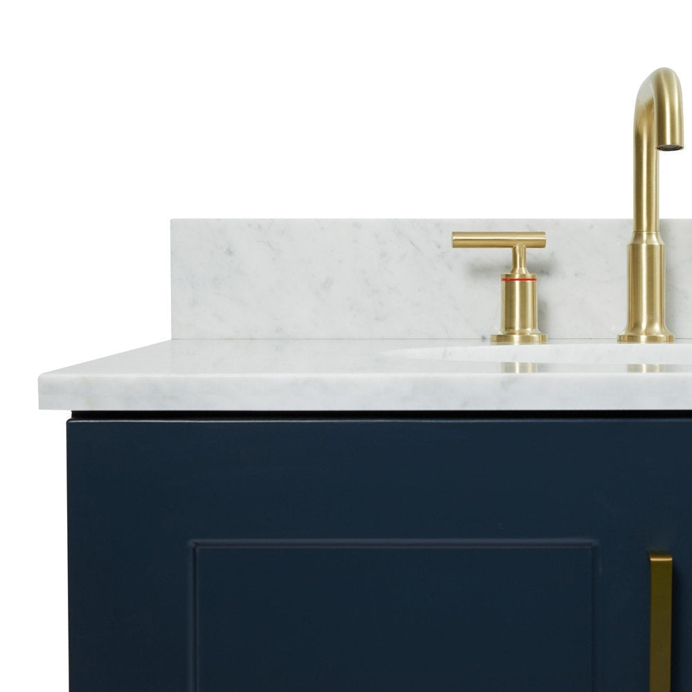 Close-up of a stone marble vanity top with backsplash and integrated sink, paired with a satin bronze faucet and T-handle above a navy solid wood cabinet with a bronze drawer pull.