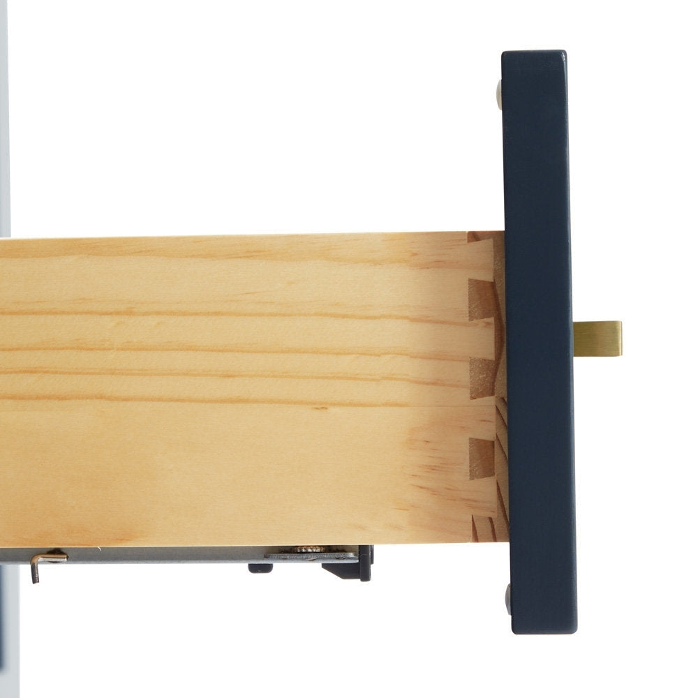 Close-up of a solid wood vanity drawer showing dovetail joinery, pale natural wood interior, dark painted drawer front, satin bronze rectangular pull and metal soft-close slide.