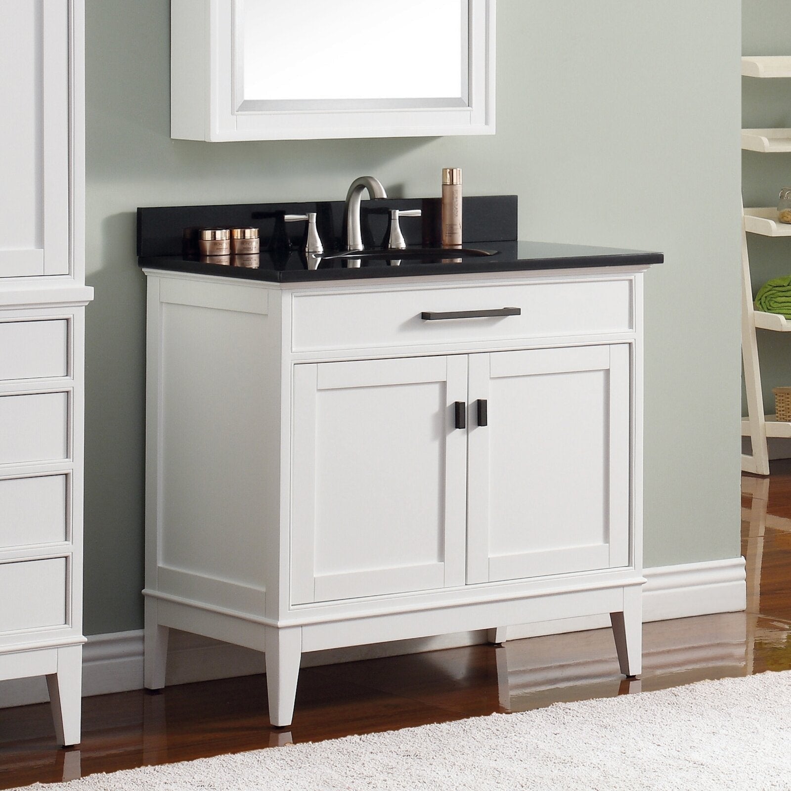 White solid wood freestanding modern bathroom vanity with a black stone countertop, undermount ceramic sink, brushed nickel faucet, and two-door storage featuring dark bar and knob handles.