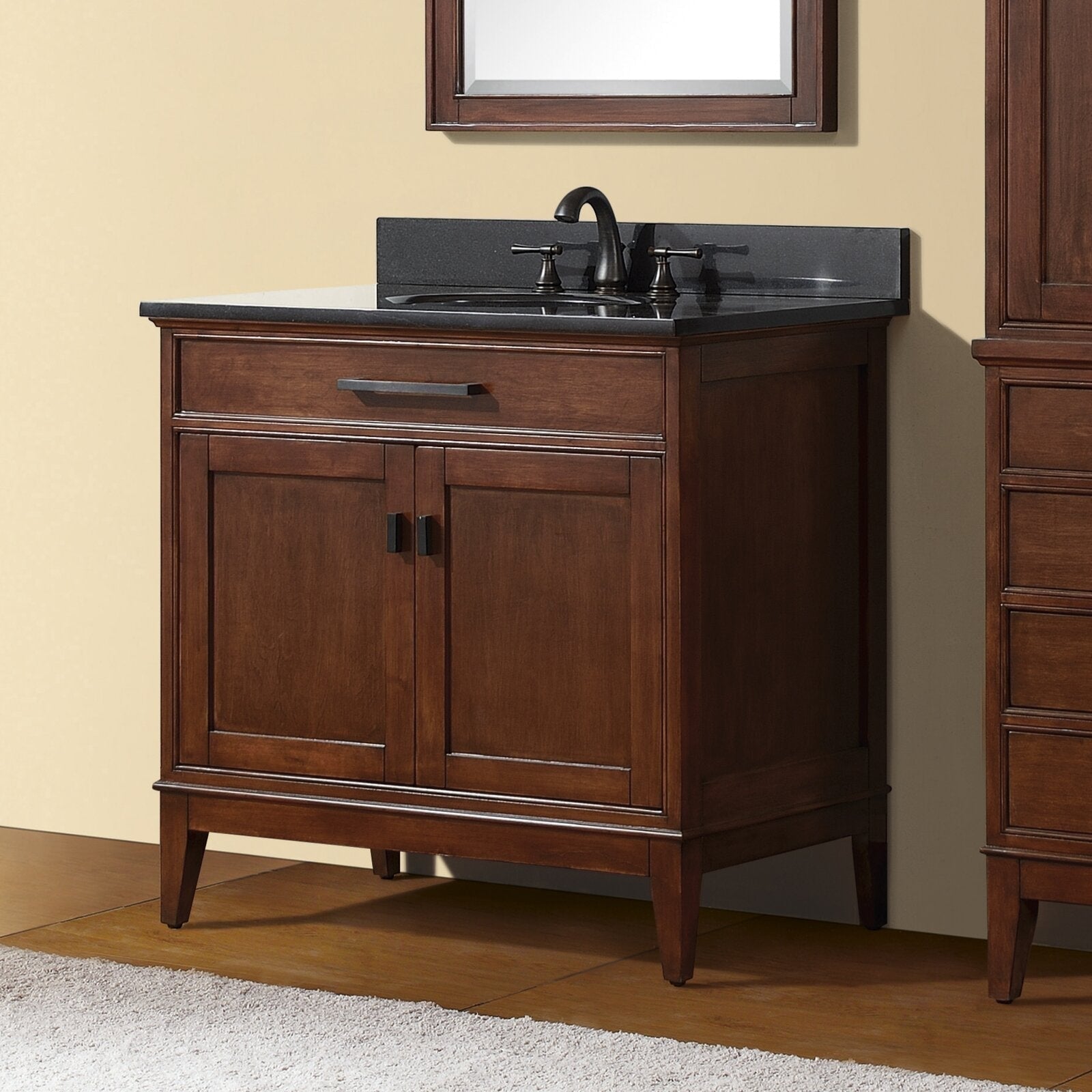 Freestanding 37-inch solid wood single-sink vanity in tobacco finish with a dark stone countertop, black integrated sink, oil-rubbed bronze faucet, two-panel cabinet doors and black rectangular hardware.