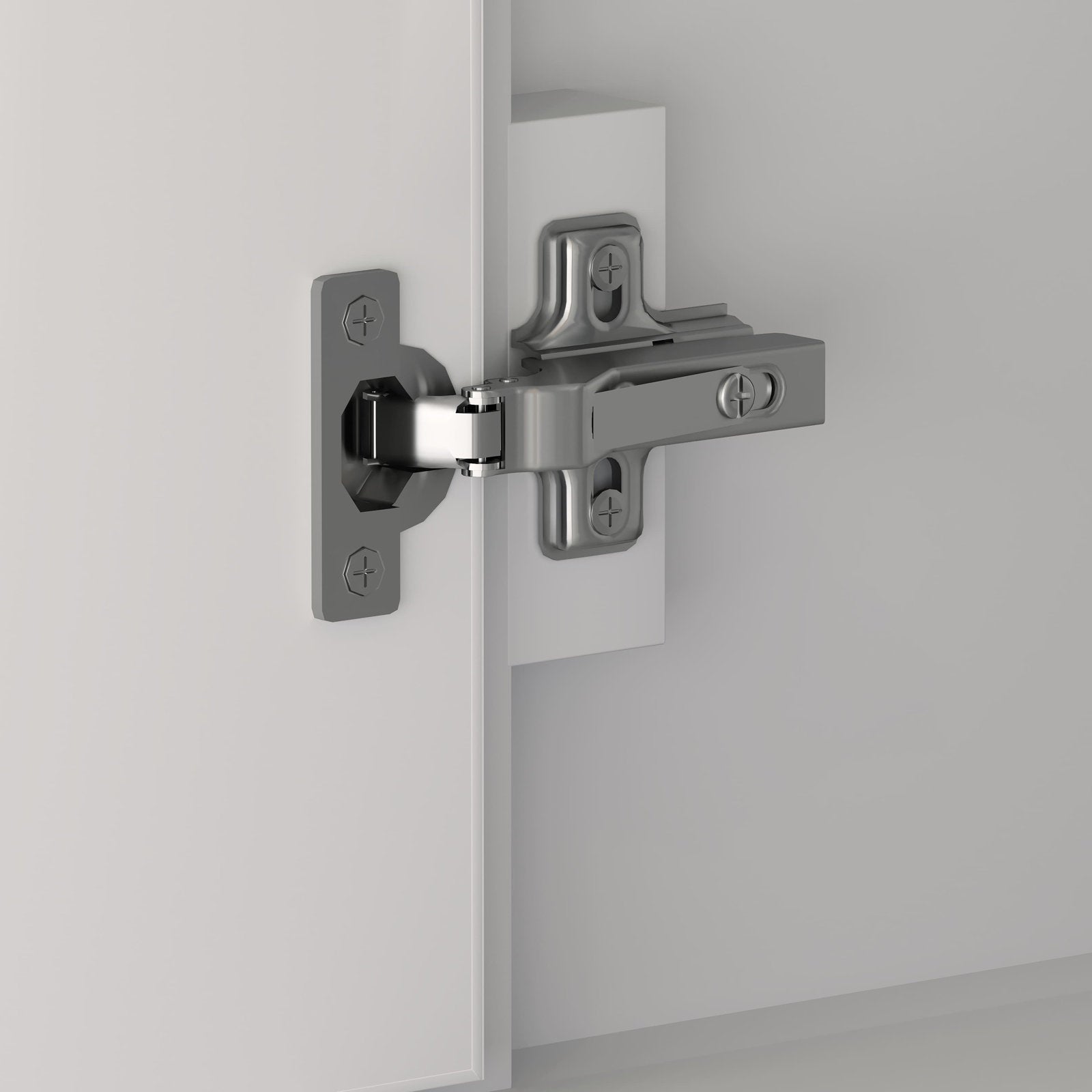 Close-up of a polished chrome metal concealed cabinet hinge mounted to the inside edge of a white wooden vanity door and frame.