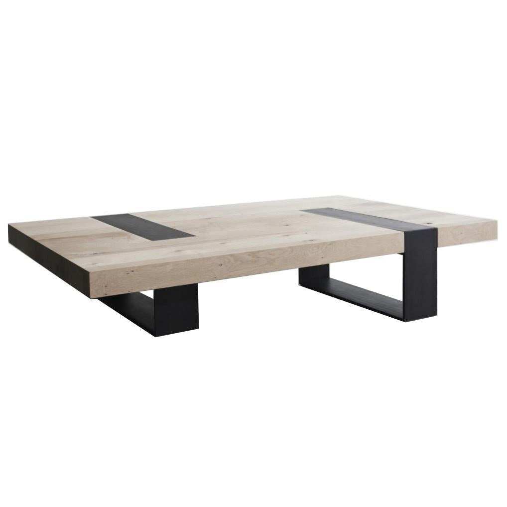 Low modern coffee table with a thick natural oak block top featuring two black steel inlay straps and matching black rectangular steel legs.