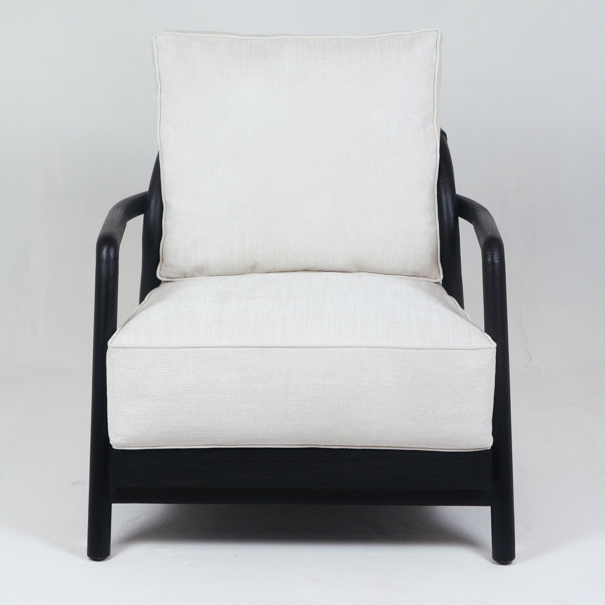 Front view of a mid-century modern armchair with a solid teak dark-stained frame and rounded arms, upholstered with thick cream fabric seat and back cushions.