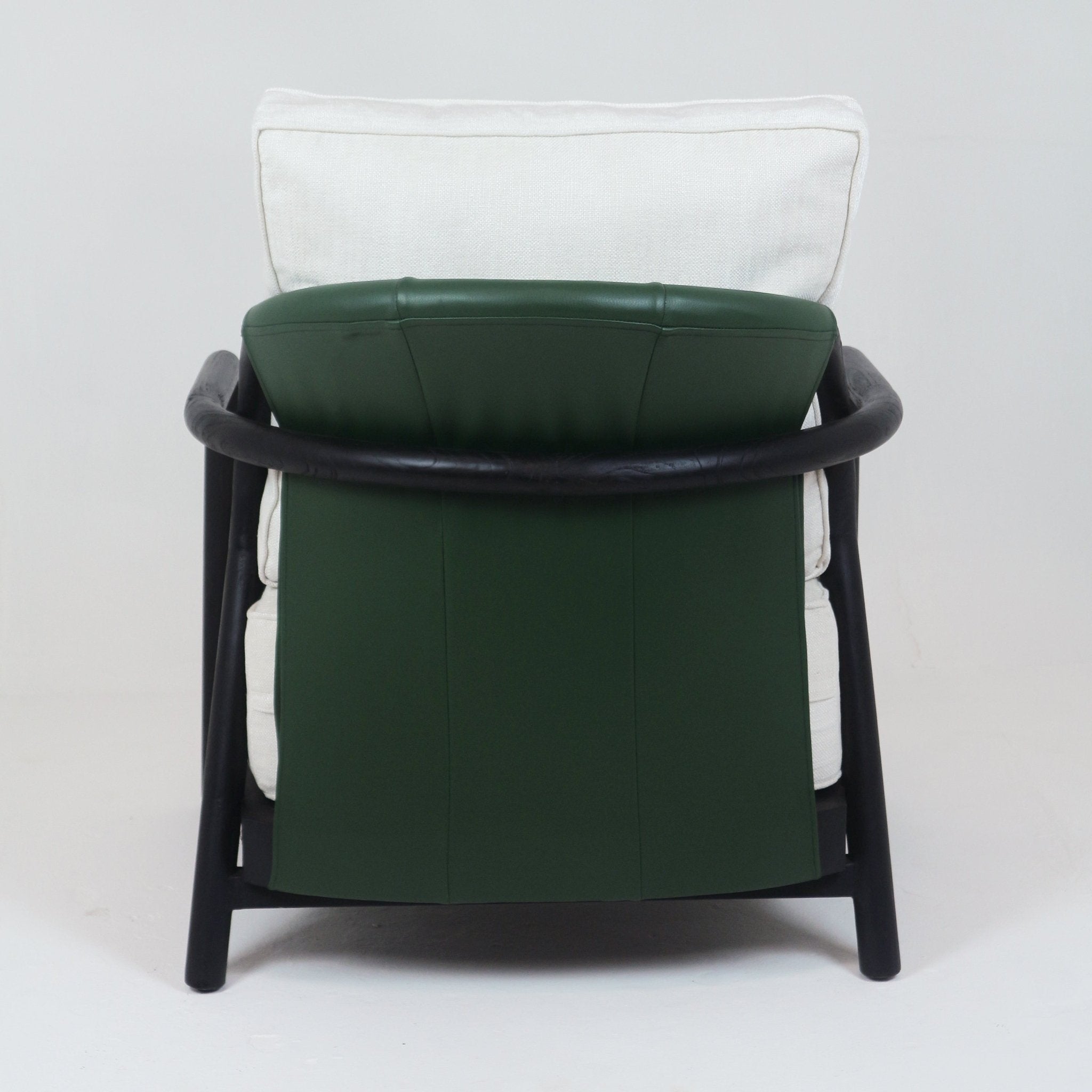 Rear view of a mid-century modern armchair with a rounded dark teak wood frame encircling a deep green leather back panel and a tall off-white fabric back cushion.