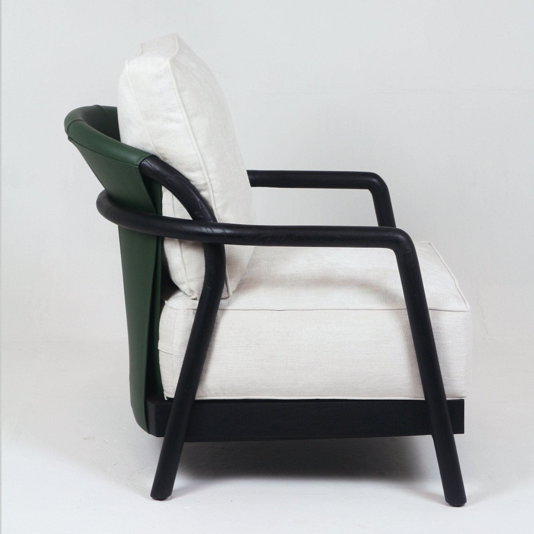 Side view of a mid-century modern armchair with a dark-stained solid teak frame, rounded black arms and legs, green leather-wrapped outer back and cushioned off-white fabric seat and back.
