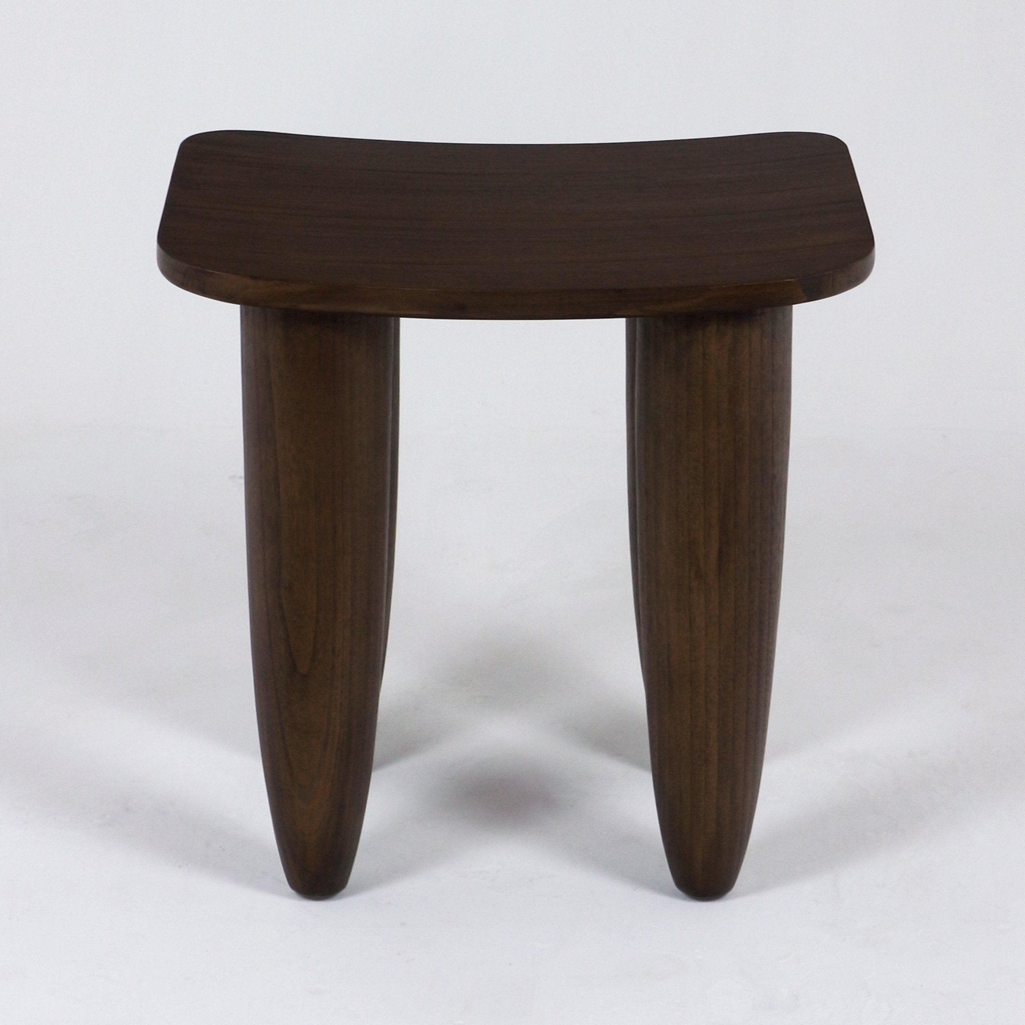 Dark mahogany solid wood side table in a modern minimalist style, with a gently curved rectangular top supported by two thick tapered rounded legs on a white background.
