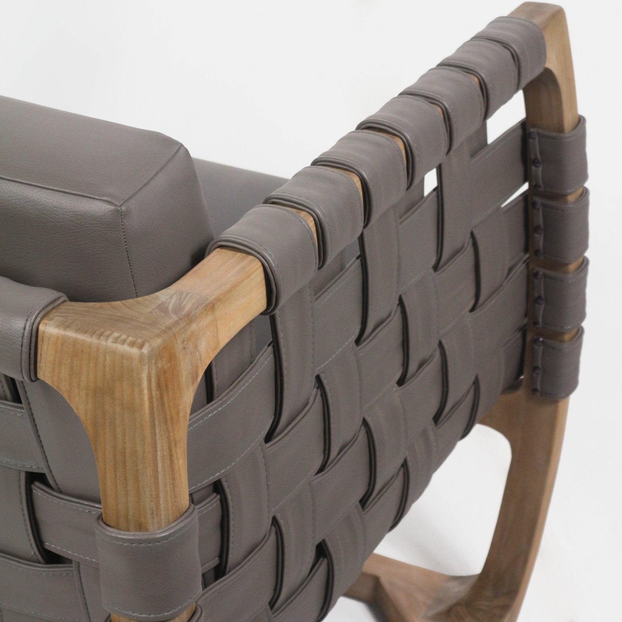 Close-up of a modern lounge chair showing taupe leather straps woven into a webbed back, wrapped and stitched around a natural solid wood frame with a matching taupe cushioned seat.