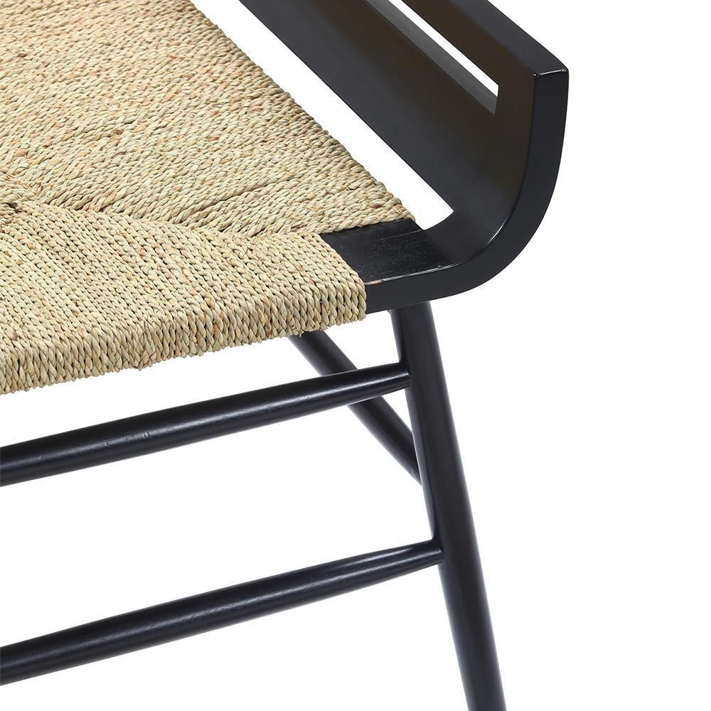 Close-up of a bench corner showing a natural woven rope seat paired with a mahogany blackwash wood frame, featuring a curved arm detail and black spindle legs with horizontal crossbars.